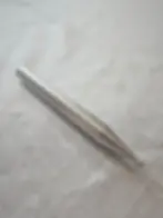 Close-up of a stainless steel facial reflexology tool on a white fabric surface