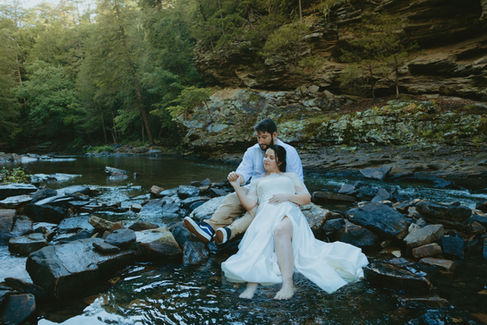 A couple shares a joyful moment in front of the cascading waterfall at Fall Creek Falls State Park, surrounded by lush greenery during their adventure elopement.