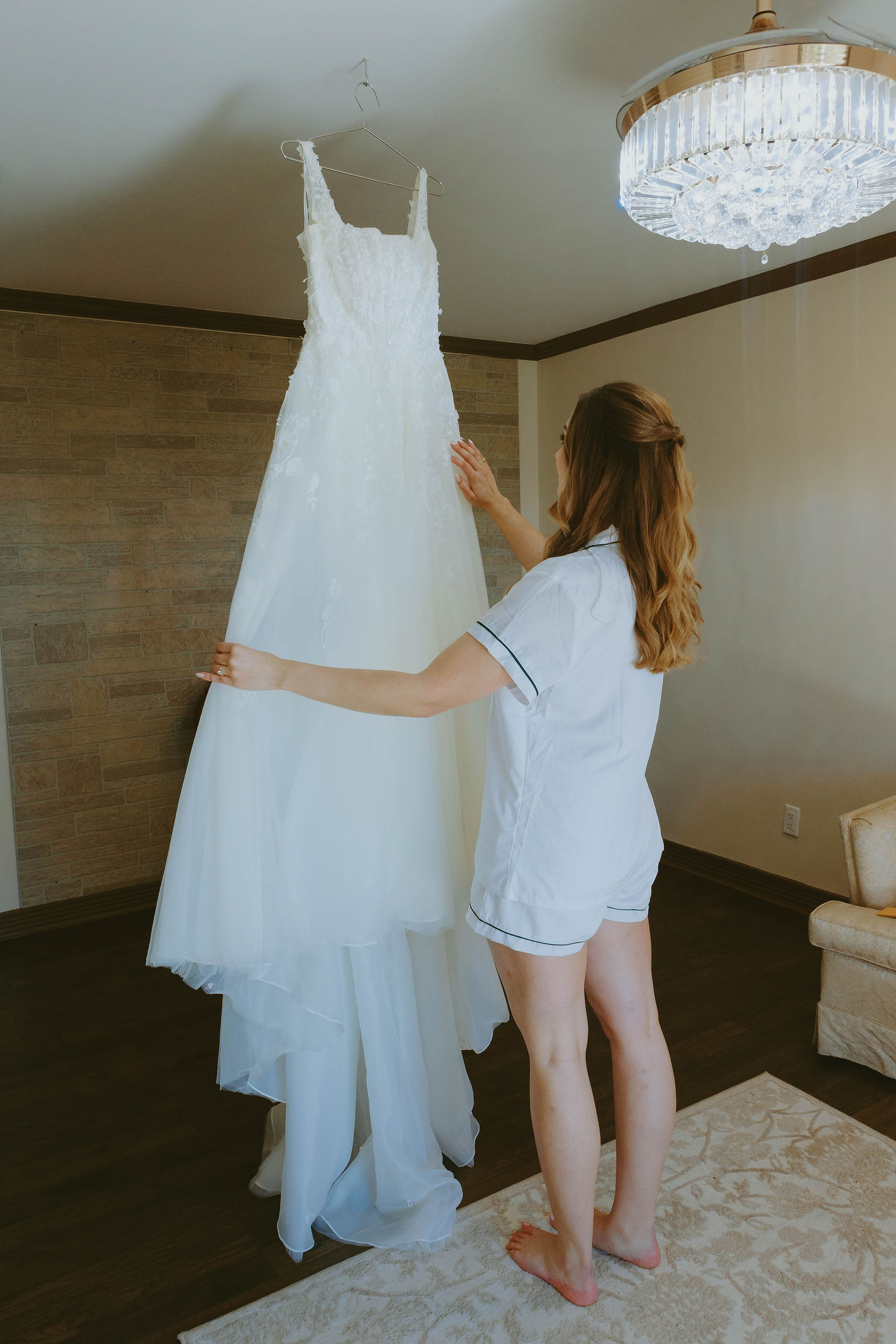 Bride standing with her dress before getting ready, taking a quiet pause on her wedding morning.