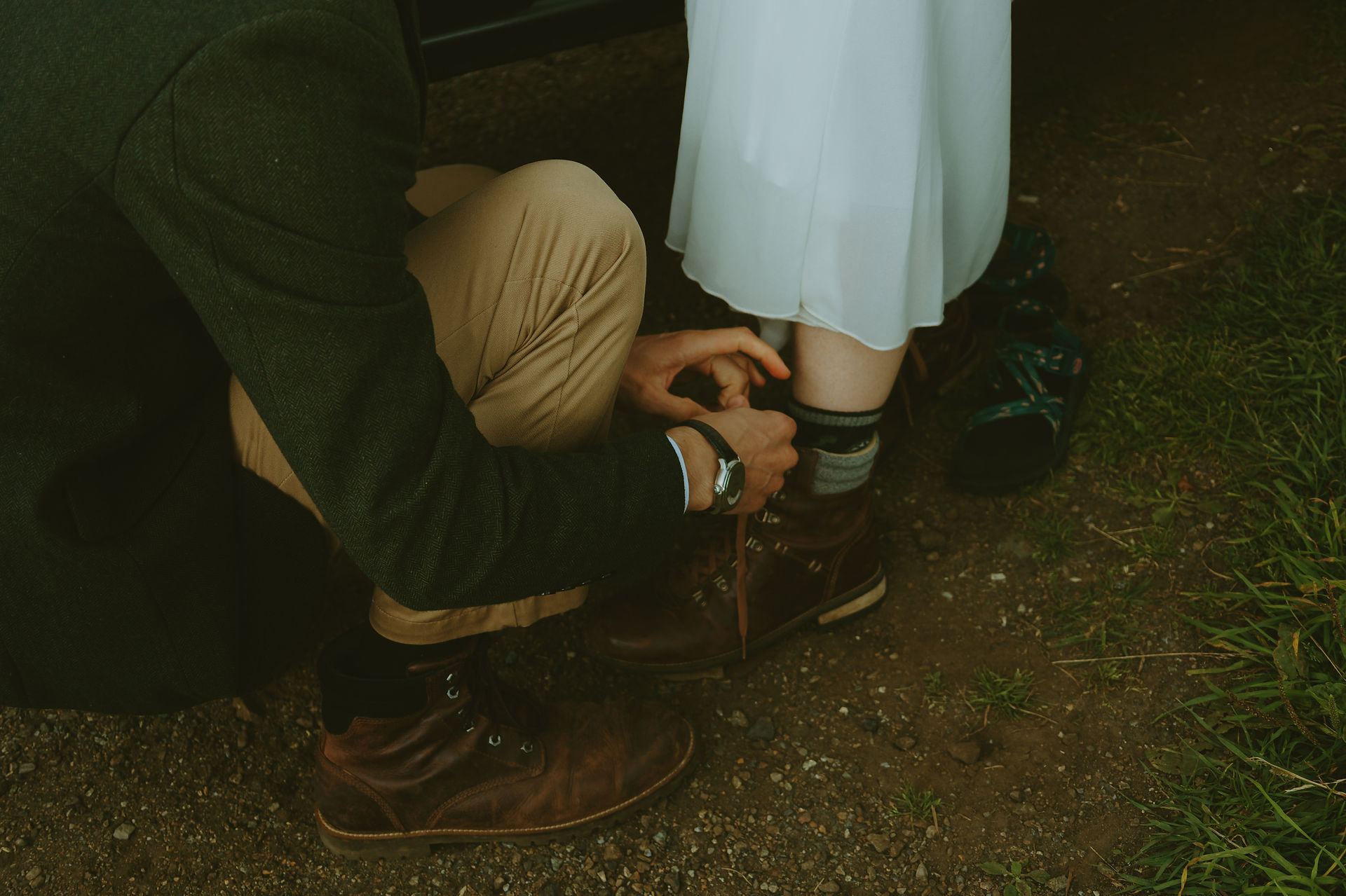Partner helping tie hiking boots as the bride gets ready for their adventure elopement