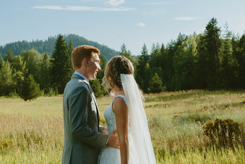 Bride and groom standing together in an open field during a quiet moment on their wedding day.