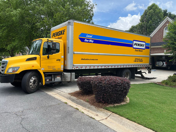 Full sized moving truck parked in driveway of home.