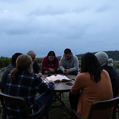 Group around table reading a book outside
