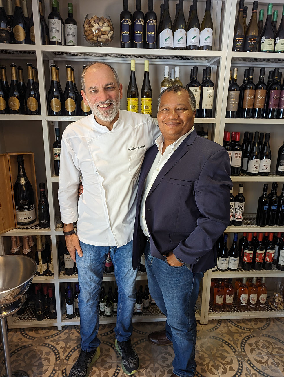 Two people smiling in front of wine shelves
