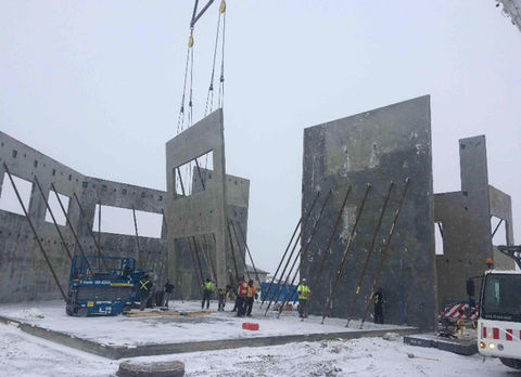 Winter panel erection underway, tilt-up concrete walls.