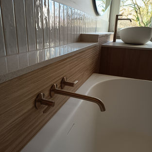 Brushed bronze bath filler with textured wall tiles