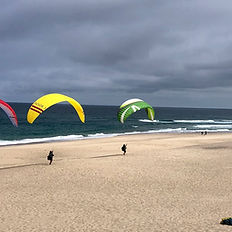 three gliders kiting on a beach