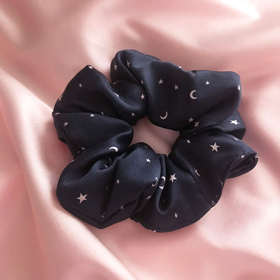 Thumbnail: A large silk scrunchie in navy blue with white stars and moon print on a pale pink silk background