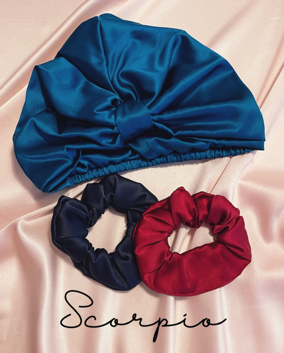 a deep teal silk sleep cap, a deep navy silk scrunchie and a deep red scrunchie against a pale pink silk background with Scorpio text