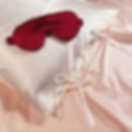 A large red mulberry silk sleeping mask on a white silk pillowcase