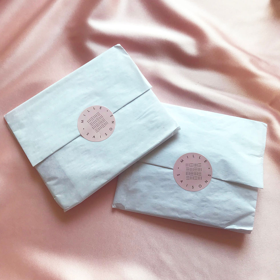 Thumbnail: Two white tissue paper packages sealed with pink Mille Saisons branded stickers