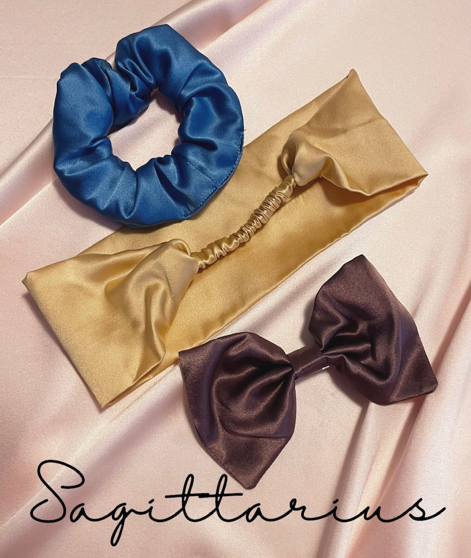 a mid blue silk scrunchie, gold silk headband and brown toned purple silk hair bow against a pale pink silk background with Sagittarius text