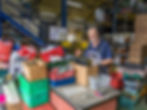 A smiling man standing next to a bench covered in tools