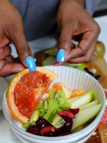 Bowl of vanilla yogurt topped with fresh kiwi, grapefrut, pears, kiwi and clementines. 