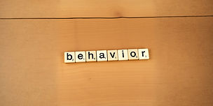 rustic, wooden game tiles spelling the word 'behavior' small and stretched to fit into hea