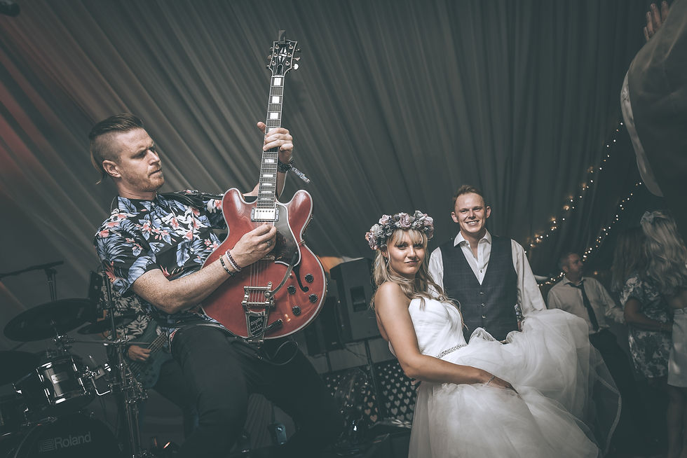 man playing guitar with bride and groom posing for a photo