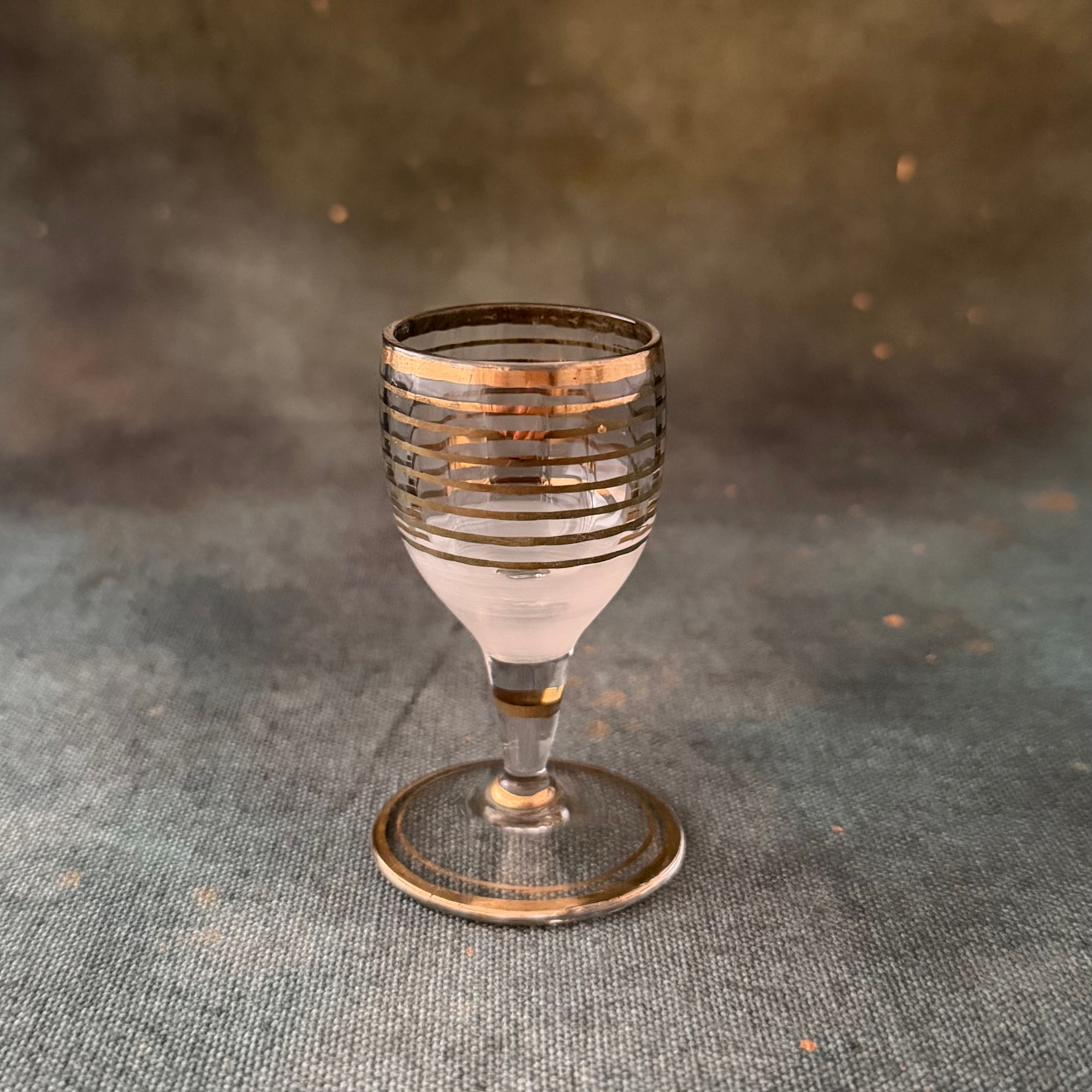 A Tiny Footed Shot Glass With Gold Stripe Detail