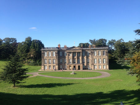 View of Calke Abbey, a grand building with lawns in front, trees behind and blue skies above. Photo Credit mizzy_moo-england