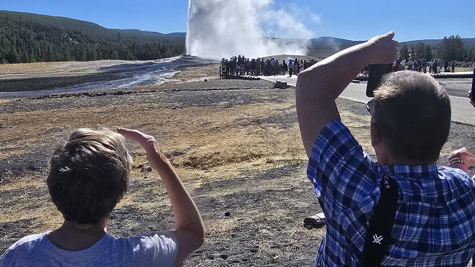 Two tour goers seeing the powerful eruption of Old Faithful Geyser.