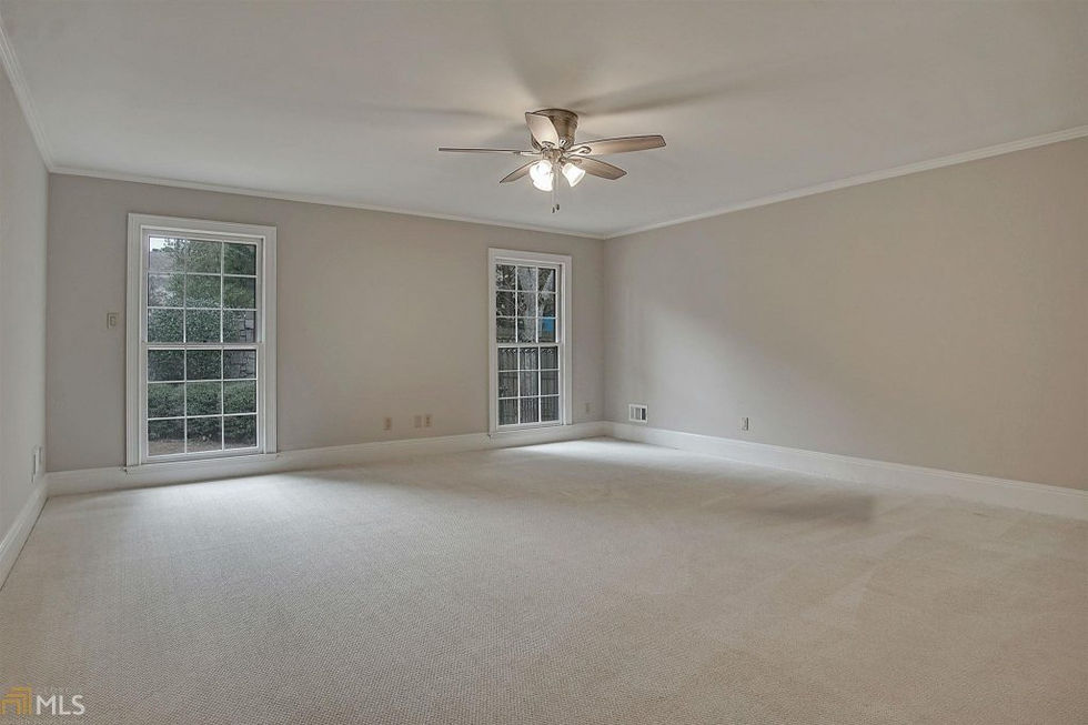 an empty room with a ceiling fan and two windows