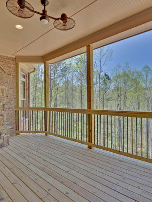 a screened in porch with a fireplace and ceiling fans