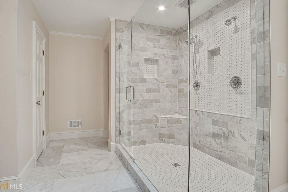 a walk in shower with marble tiles and a glass door