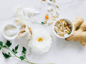 calming picture of a white flower, ginger root, garlic bulb, white container of supplements