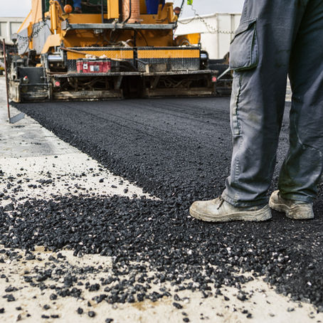 Person standing between newly paved asphalt and old