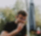 Ein Mann mit Brille trägt ein ODWLDR-T-Shirt und isst ein Stück Pizza. Er sitzt vor einem geschlossenen Sonnenschirm. Auf dem Tisch steht eine PET-Flasche.
