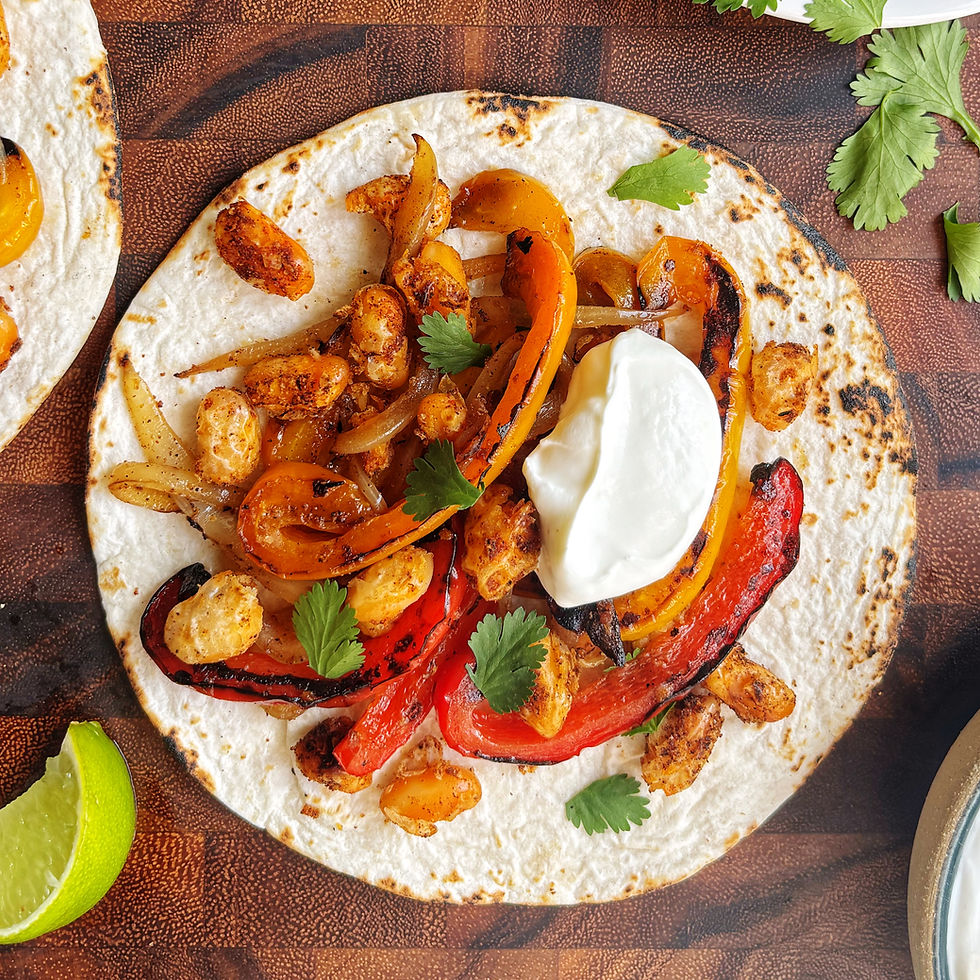 A white bean fajita with blistered peppers and onions, topped with sour cream and cilantro.