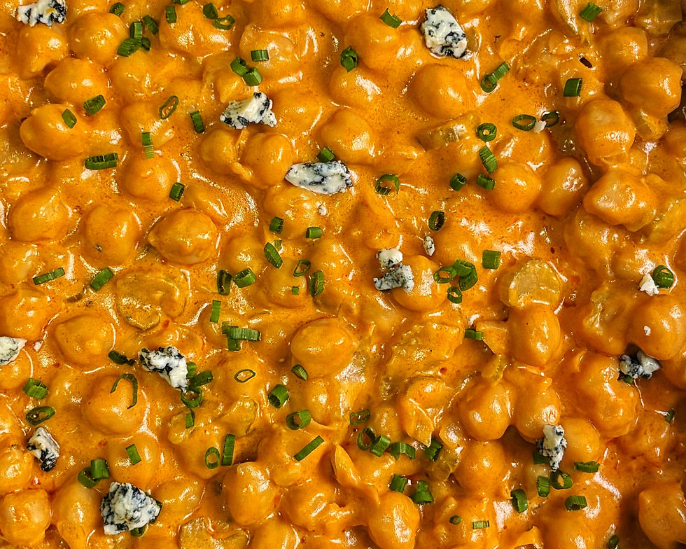 Buffalo chickpeas topped with chives and blue cheese on a plate with rice.