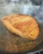 Flank steak searing in a cast iron pan.