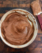 Chocolate mousse in a big white bowl with a spatula beside it.