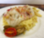 Cod fillet on a bed of couscous with a garnish of roasted fennel, tomatoes, and olives.