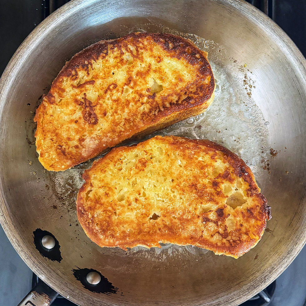 Door-stopping overnight french toast frying in butter in a silver pan.