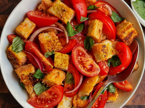 Garlic bread panzanella salad with garlic bread croutons, red onions, and basil in a white bowl.