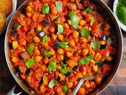 Ratatouille with chickpeas topped with basil in a pan.