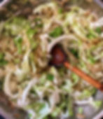 Overhead view of cabbage and onion cooking in a pan with a wooden spoon.