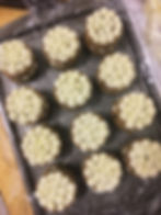 Baking sheet with twelve filled and frosted mini zucchini spice cakes.