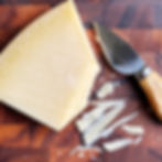 Parmesan cheese on a cutting board with a cheese knife.
