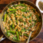 White beans, asparagus, and peas topped with parmesan and black pepper on a white plate with a fork.