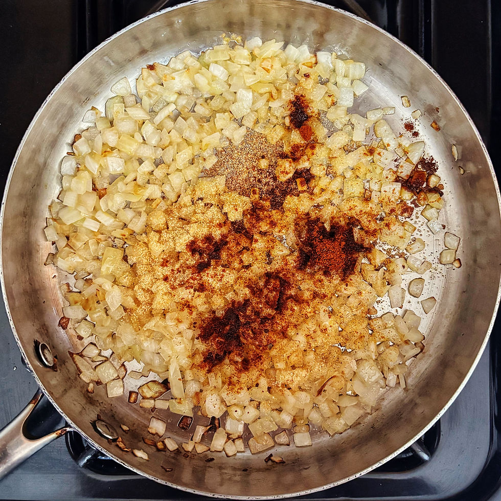 Cooked-down onions sprinkled with garlic powder and paprika in a pan.