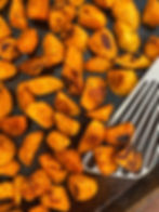 Roasted sweet potatoes on a baking sheet with a metal spatula.