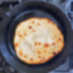 Flatbread cooking in a cast iron pan.