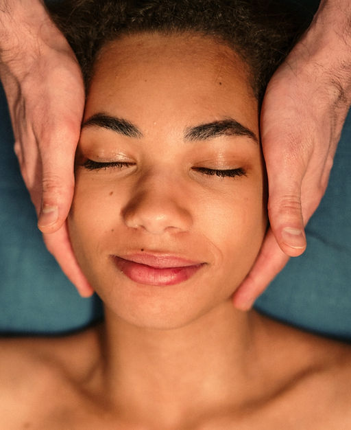 A woman rests face up on a massage table while the practitioner applies a manual osteopathic technique.