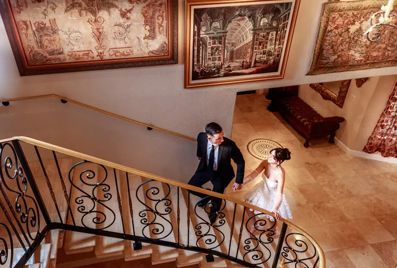 A wedding photographer in Miami takes a photo of a couple walking upstairs inside the Mansion at Villa Toscana Miami, the best venue for wedding photos and engagement photos.