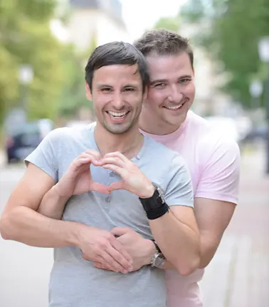 Smiling LGBTQ couple embracing outdoors, symbolizing intended parents supported by Giving Tree Surrogacy