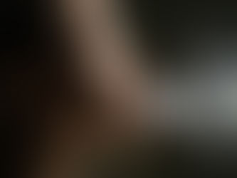 Close-up side profile of a woman exhaling a visible stream of breath or vapor, illustrating pursed lip breathing method against a dark background.