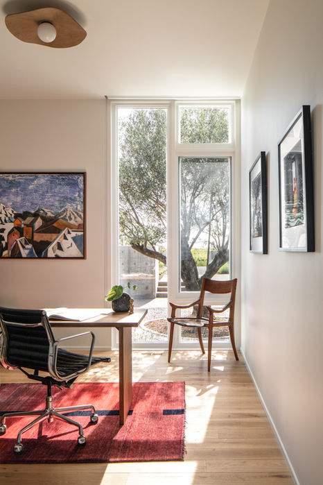 Custom home office with modern desk, red rug, and floor-to-ceiling windows overlooking olive trees at Hillside House in Oregon’s Willamette Valley.