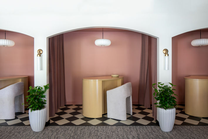 Arched consultation spaces with blush walls, custom furniture, and layered lighting at Skin by Lovely medical spa designed by JHL Design.